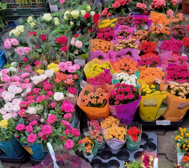 A vibrant display of fresh flowers arranged in various colorful bouquets at the flower shop, including pink, white, yellow, and orange blooms. The flowers consist of roses, carnations, and small flori