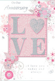 In this softly romantic anniversary card, enduring love is celebrated through gentle colour and graceful design. The card blends pastel pinks with silvery greys and warm whites, creating a tender, almost hushed atmosphere reminiscent of a calm evening stroll through Erith's quieter streets. At the centre, the word LOVE is elegantly formed in raised, soft glitter, the surface textured yet even, like finely sugared petals. The letter O is replaced by a shimmering silver heart, slightly more pronounced and tactile than the other letters, drawing attention to the emotional core of the message. Around this focal word, delicate blossoms in blush and mauve unfurl with the looseness of watercolour painting; their outlines are defined yet softened, allowing the colours to blend gently into the background. Long, curling lines and slim vines weave among the flowers, hinting at movement and care, as if an invisible hand is arranging a bouquet in slow, measured gestures. Tiny details-scattered petals, swirling motifs, and the faint shapes of butterflies-add an airy playfulness, giving the design a sense of life without overwhelming the calm. The backdrop is a soft, even pink, fading subtly nearer the edges, supporting the floral artwork and glittered lettering. Above and below the central motif sit two lines of text in graceful script: On Our Anniversary and I love you today and always. The handwriting-style font is refined but easy to read, echoing the warmth and sincerity of a partner's handwritten note tucked beside a bouquet from a local Erith florist. The overall composition feels like a gentle whisper of celebration, ideal for marking another year of shared memories and heartfelt promises.